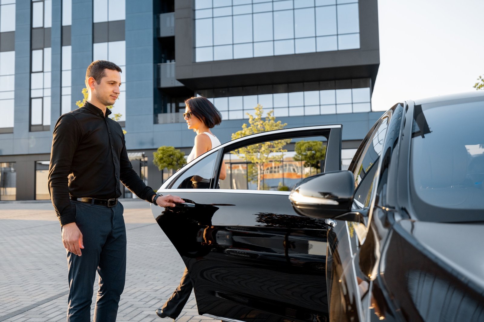 Chauffeur helps an elegant business woman gets in car